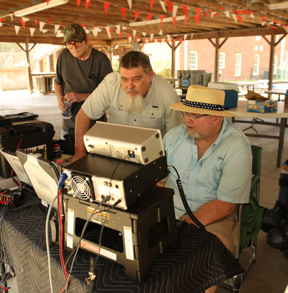 James Bullard, KC4ZIE, working amateur radio while others look on at club field day, 2024.