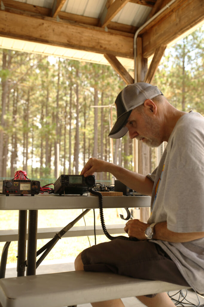 Ted Lathan, KB4CIT, working amateur radio while others look on at club field day, 2024.