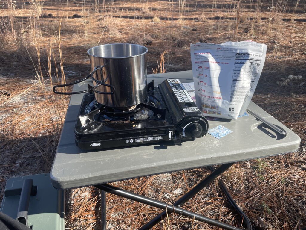 Camp cook stove with boiling pot and dinner mix.
